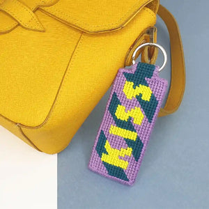 Kit canevas porte-clés Kiss réalisé et présenté sur un sac à main comme bag charms.